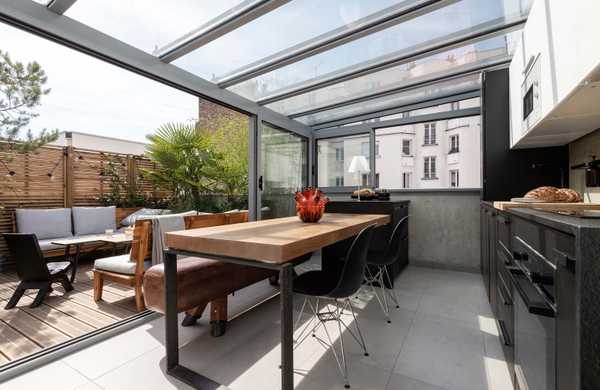 Aménagement d'un toit-terrasse avec une véranda qui abrite une cuisine / salle à manger