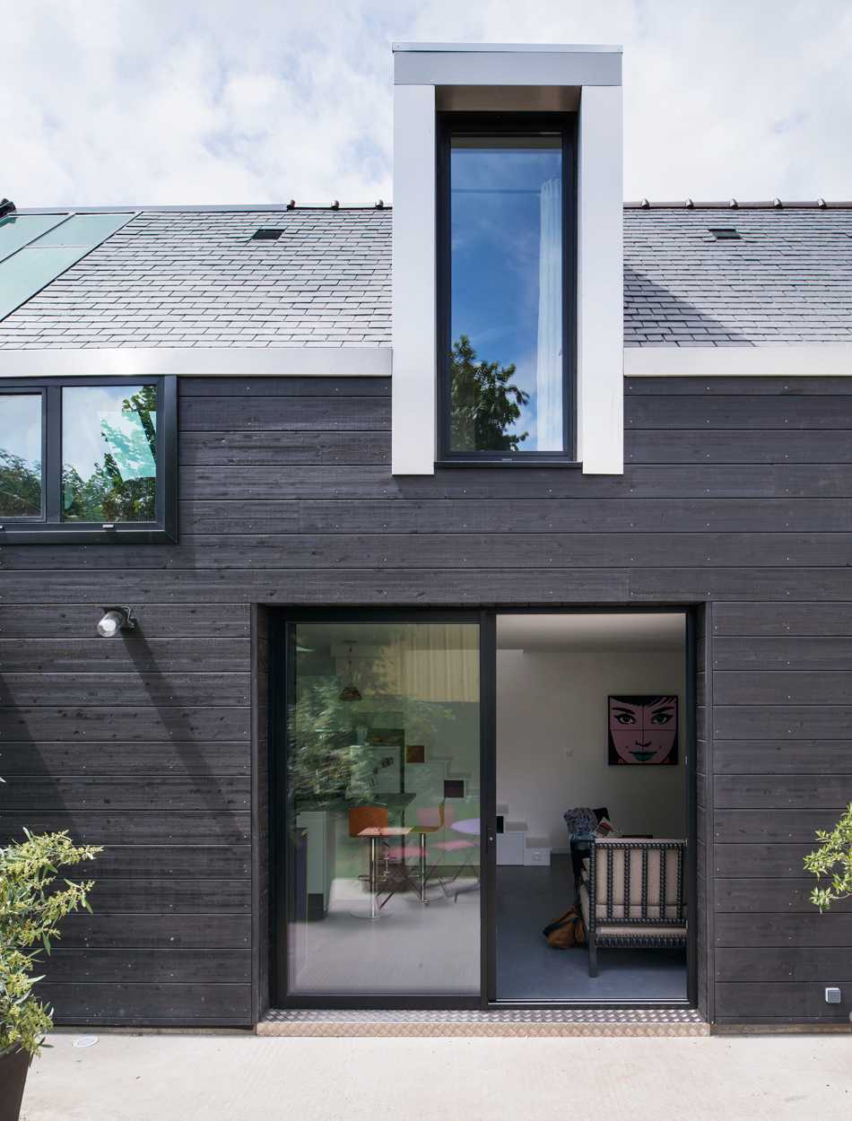 Maison d'architecte avec ossature et charpente en bois de couleur sombre